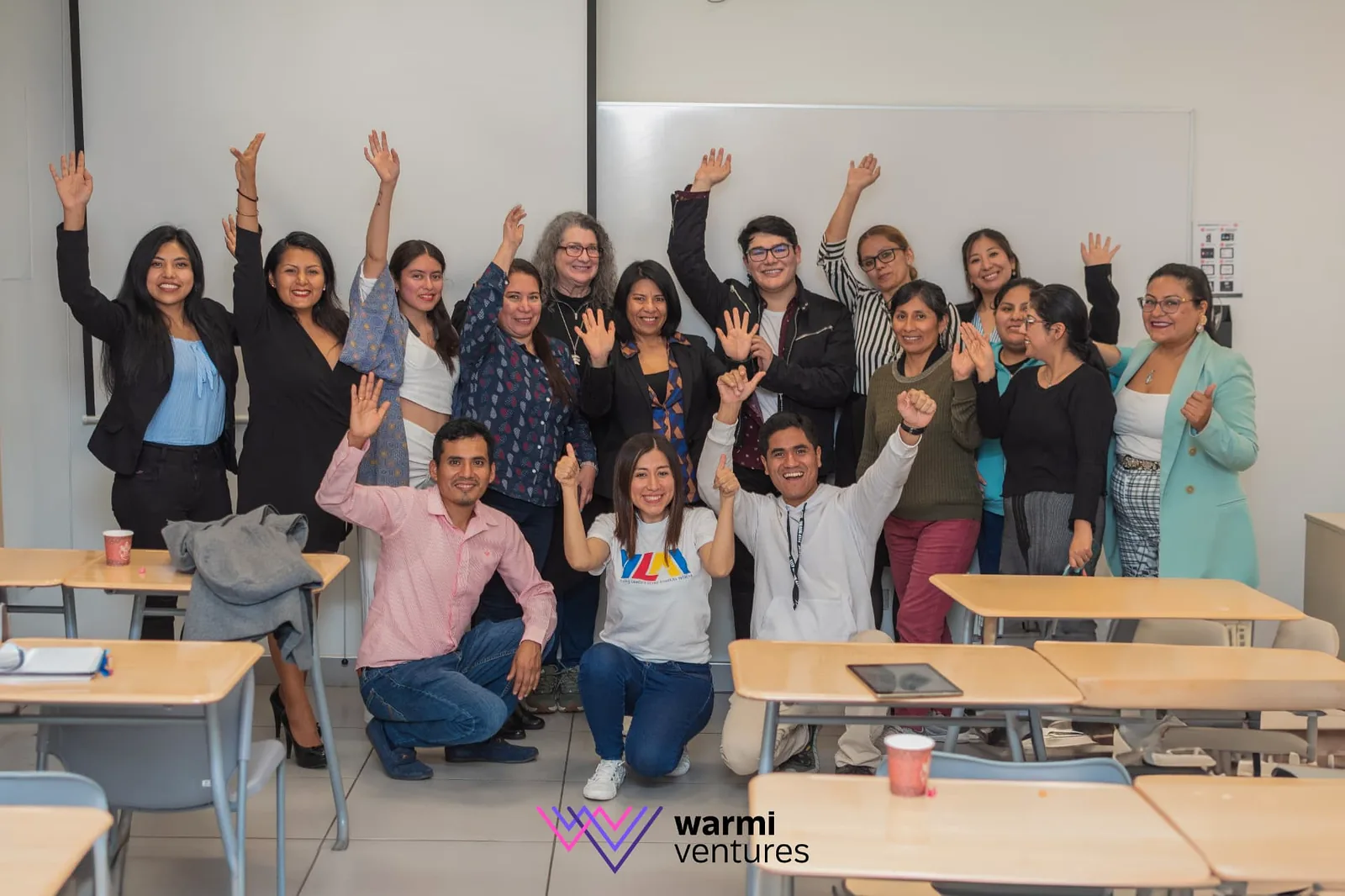 Participantes celebrando con las manos en alto al terminar una clase presencial